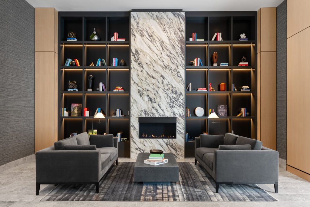 A lobby with two couches in front of a large bookcase and fireplace