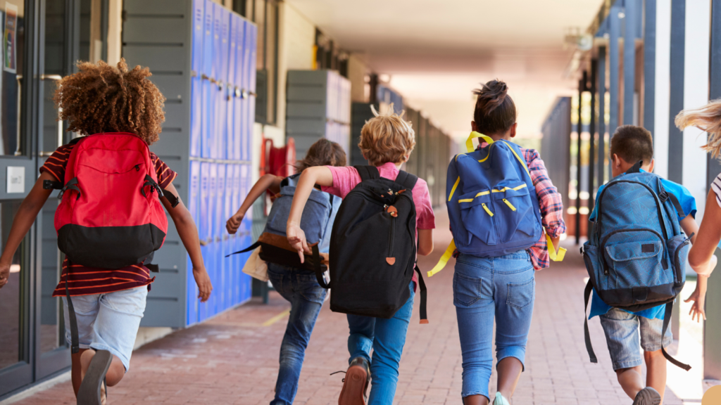 Elementary School students running through the hallway with their backpacks on