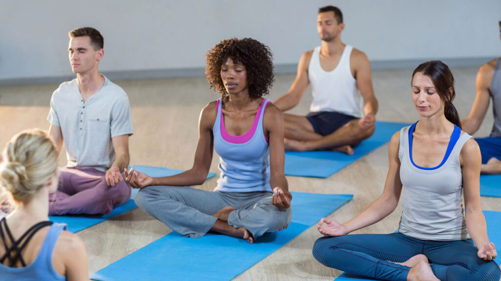 Several people sitting on yoga mats in a yoga studio meditating