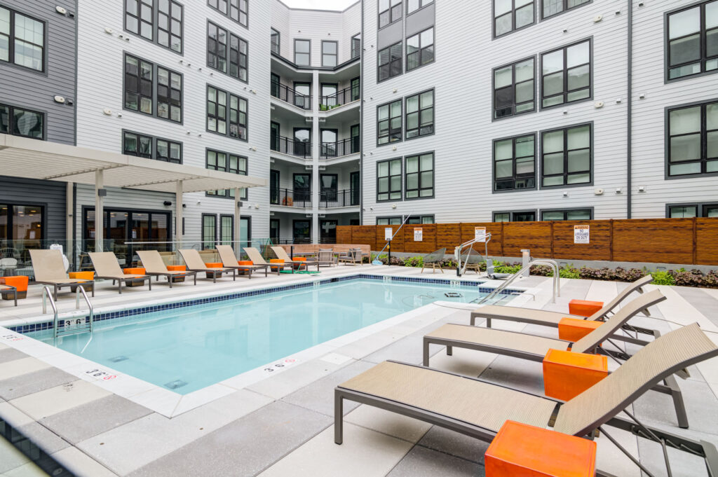 A pool with lounge chairs outside of The Whit apartments