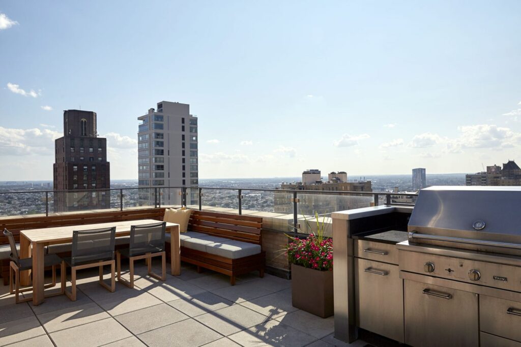 View of Philadelphia from ICON's Sky Deck with a table, chairs, plants, and a grill